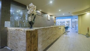 Zona de recepción con mostrador de madera, un reloj y un cartel que indica la recepción.