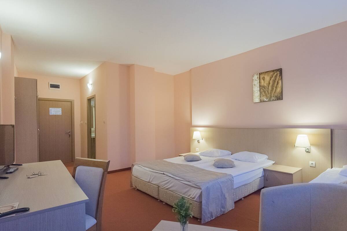 Ett hotellrum med en säng, sängbord, ett skrivbord och en stol.