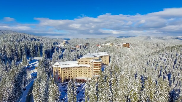Un hotel rodeado de árboles y montañas cubiertas de nieve.
