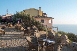 A coastal property with wicker furniture, a stone pathway, and a view of the sea.