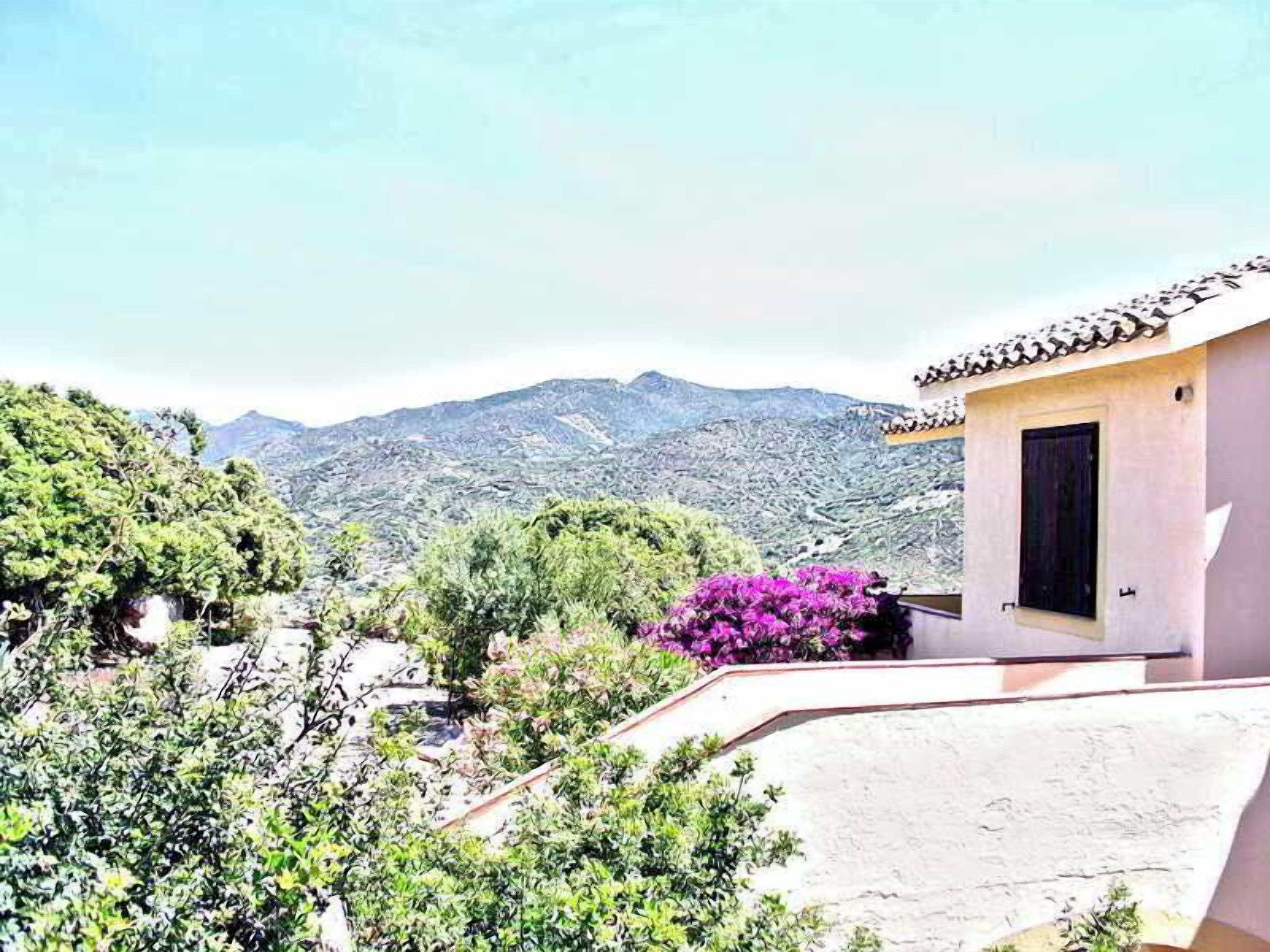A hillside villa with a small building featuring a tiled roof and a window.