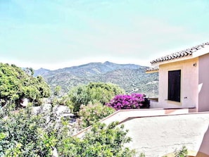 A hillside villa with a small building featuring a tiled roof and a window.