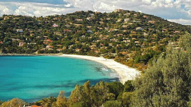 A coastal town with houses on a hillside overlooking a beach.