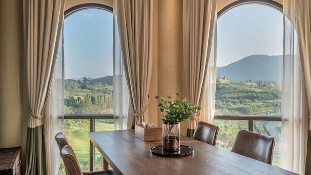 A dining area with a table, chairs, and a view of a mountainous landscape through large windows. - Toscana Piazza by Toscana Valley (Pak Chong)