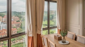 Un comedor con un ventanal grande, cortinas y una mesa con sillas.