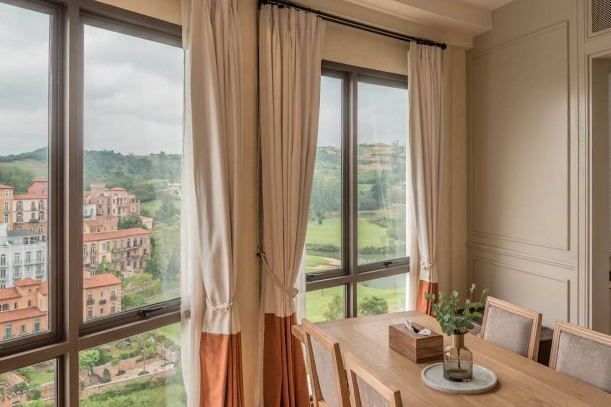 A dining area with a large window, curtains, and a table with chairs.