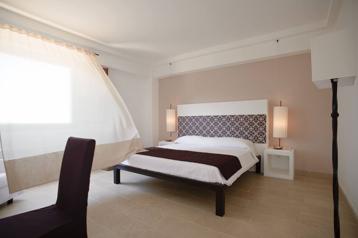 A bedroom with a bed, bedside tables, a chair, and a floor lamp.