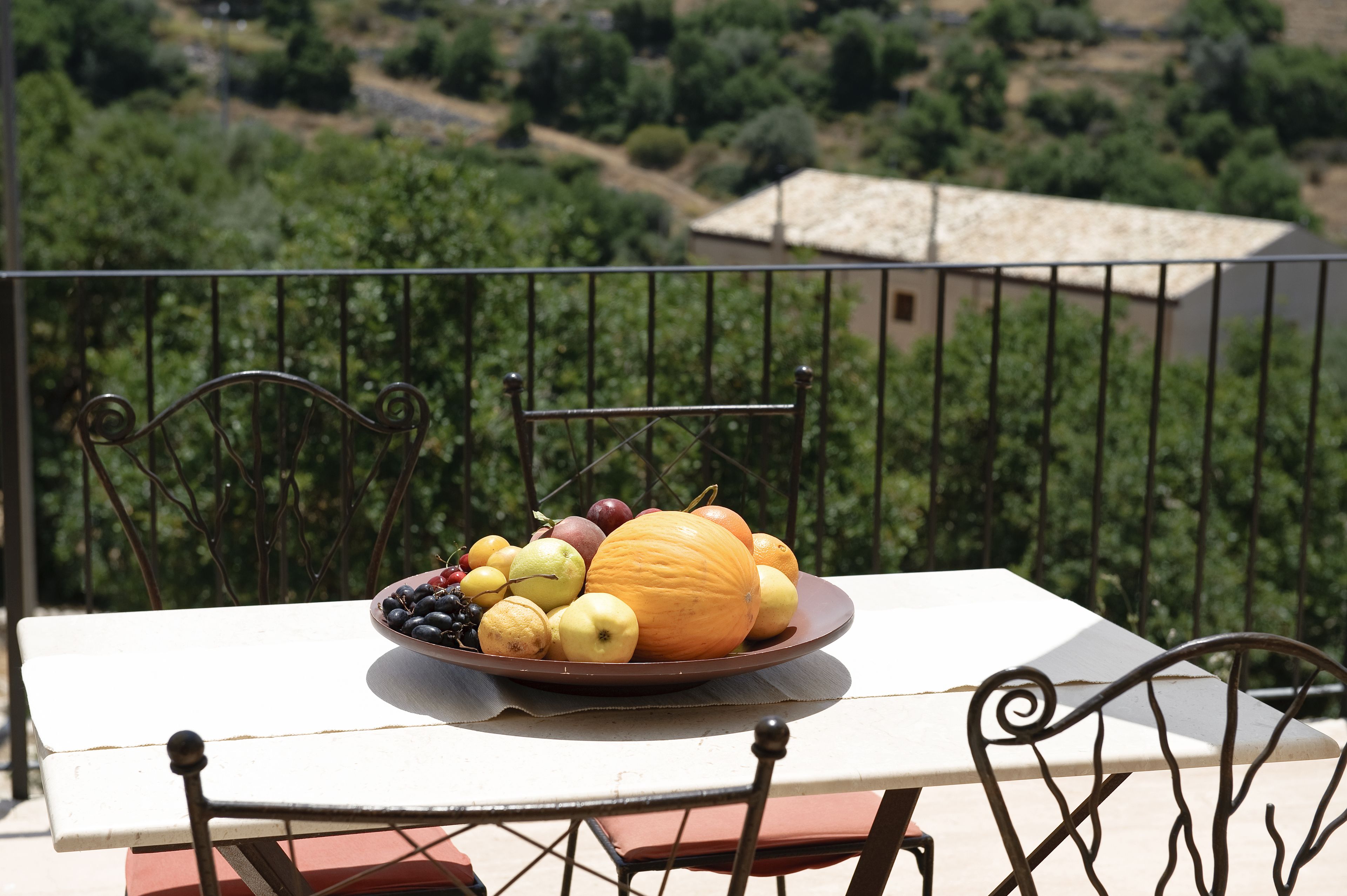 Ein Tisch mit Obstschale auf einem Balkon mit Blick auf einen Weinberg.