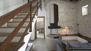 A staircase with wooden railings leading to a stone-walled room with a fireplace, a sofa, and a lamp. - Relais Parco Cavalonga (Ragusa)
