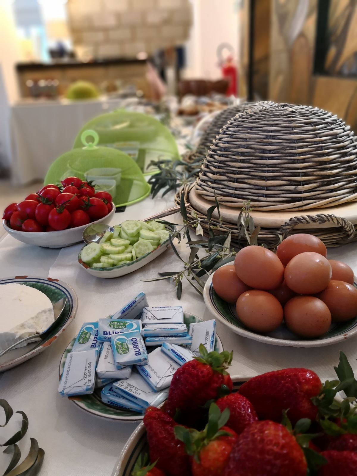 Ein Tisch mit verschiedenen Speisen, darunter Tomaten, Gurken, Eier, Erdbeeren und verpackten Snacks.