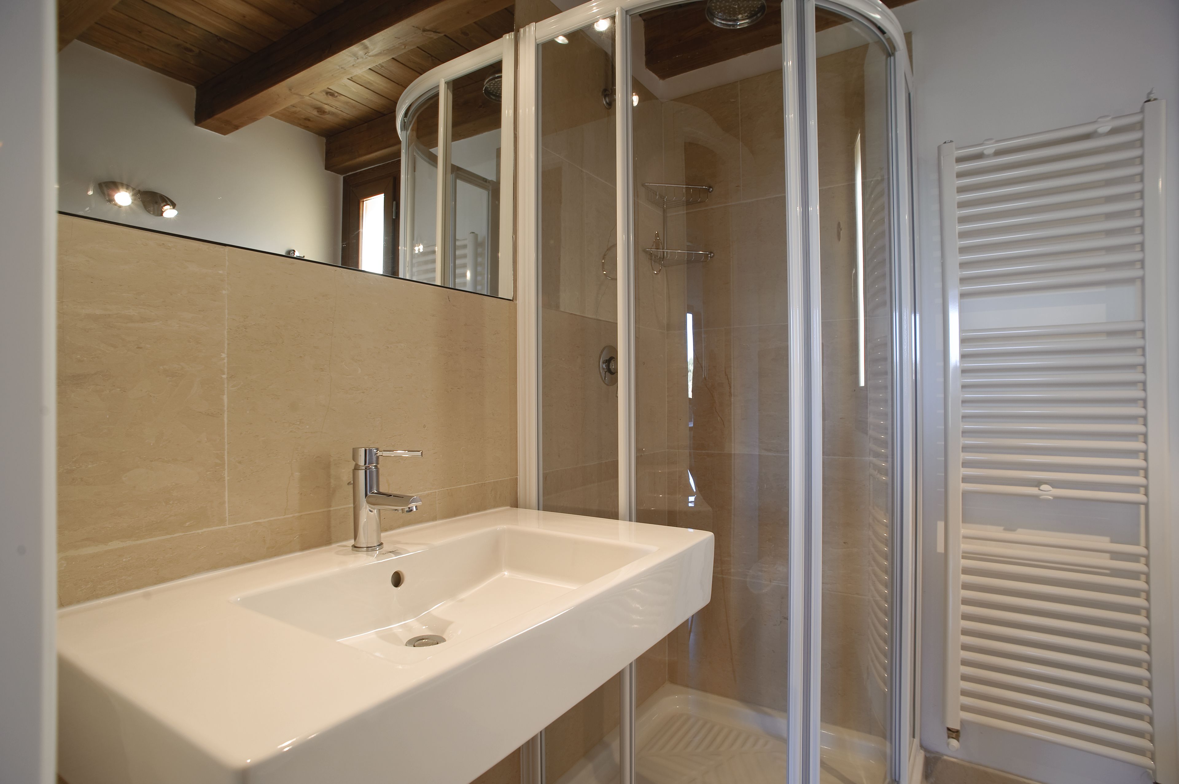 Un baño moderno con lavamanos blanco, cabina de ducha de vidrio y toallero.