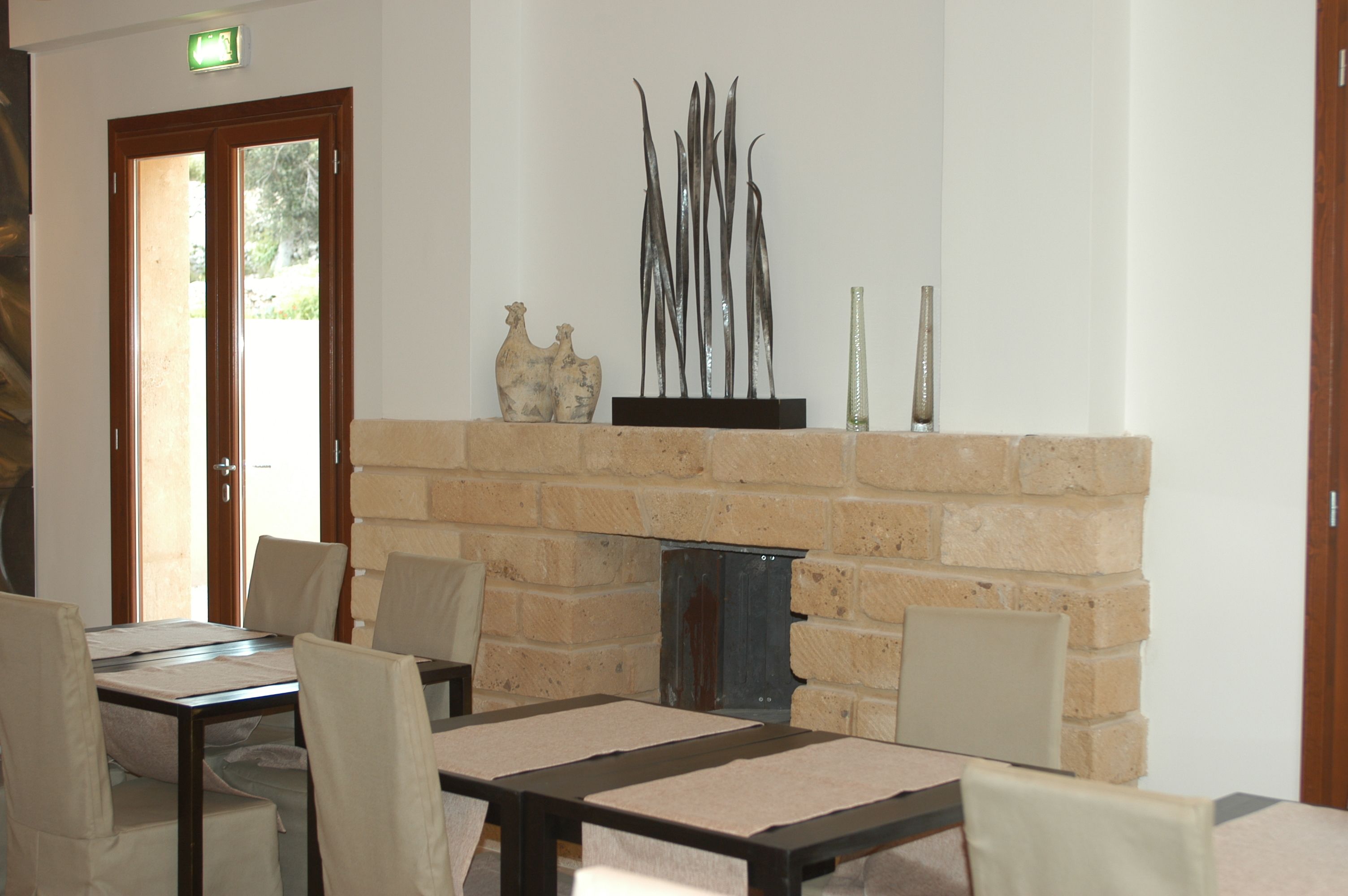 A dining area with a brick fireplace, a table with chairs, and decorative items on the mantel.