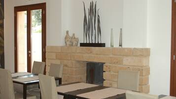 A dining area with a brick fireplace, a table with chairs, and decorative items on the mantel.