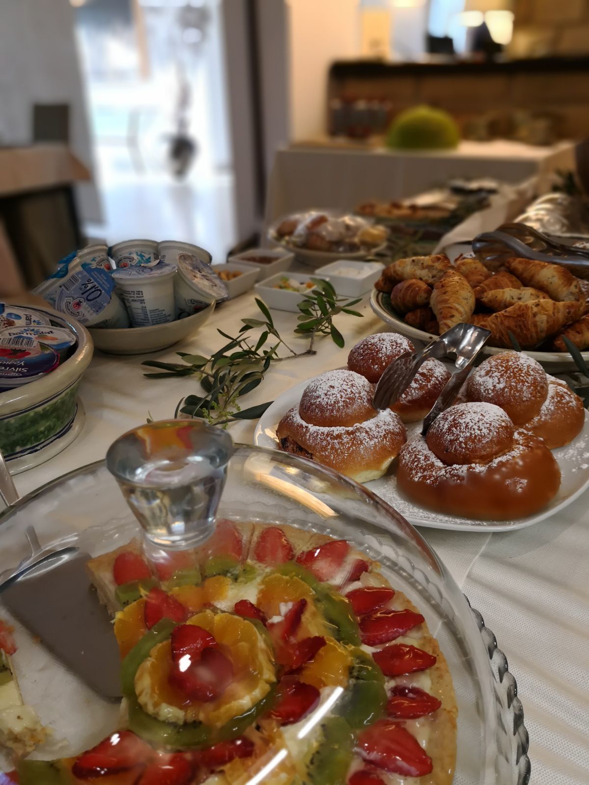 Un tavolo per buffet con diversi cibi, tra cui pasticcini, una torta di frutta e latticini.