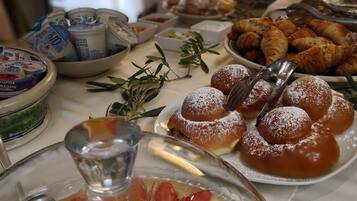 Un tavolo per buffet con diversi cibi, tra cui pasticcini, una torta di frutta e latticini.