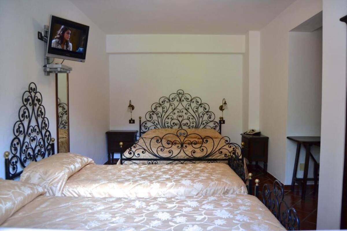 Un dormitorio con cama, televisor montado en la pared y un cabecero decorativo de metal.