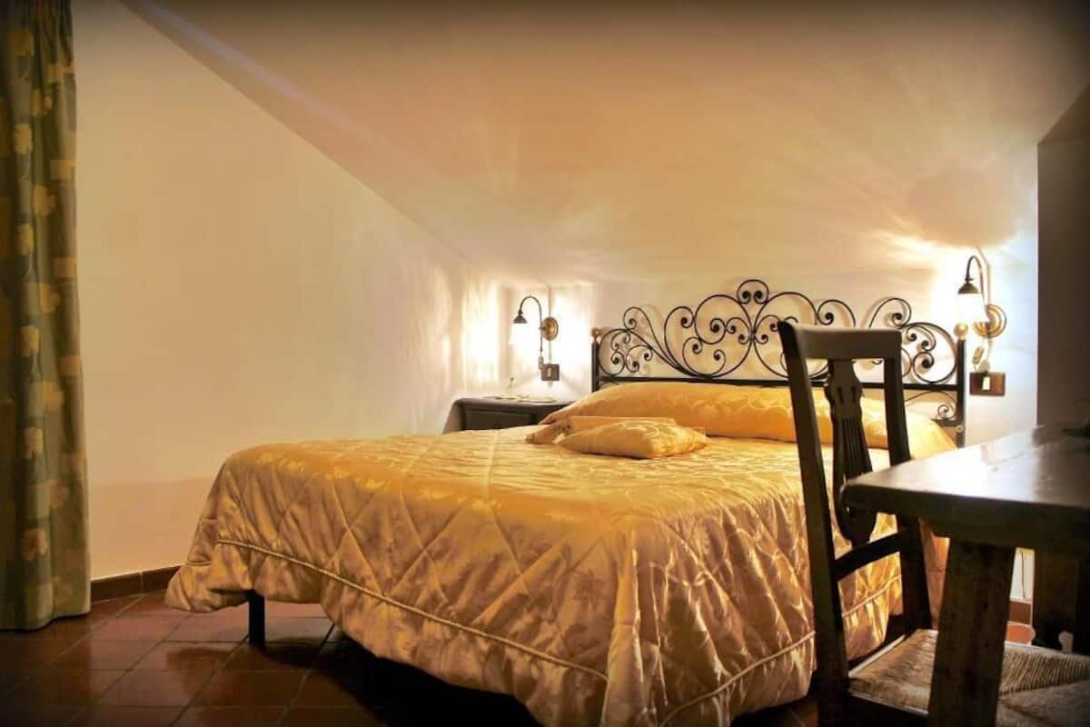 Un dormitorio con cama, una silla, una mesa y una mesita de noche.