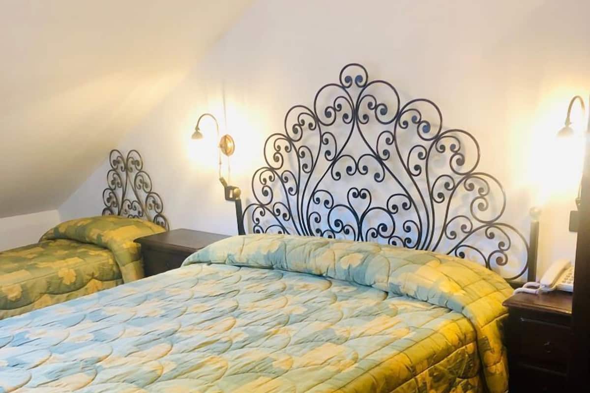Un dormitorio con cama, mesita de noche y lámpara de pared.