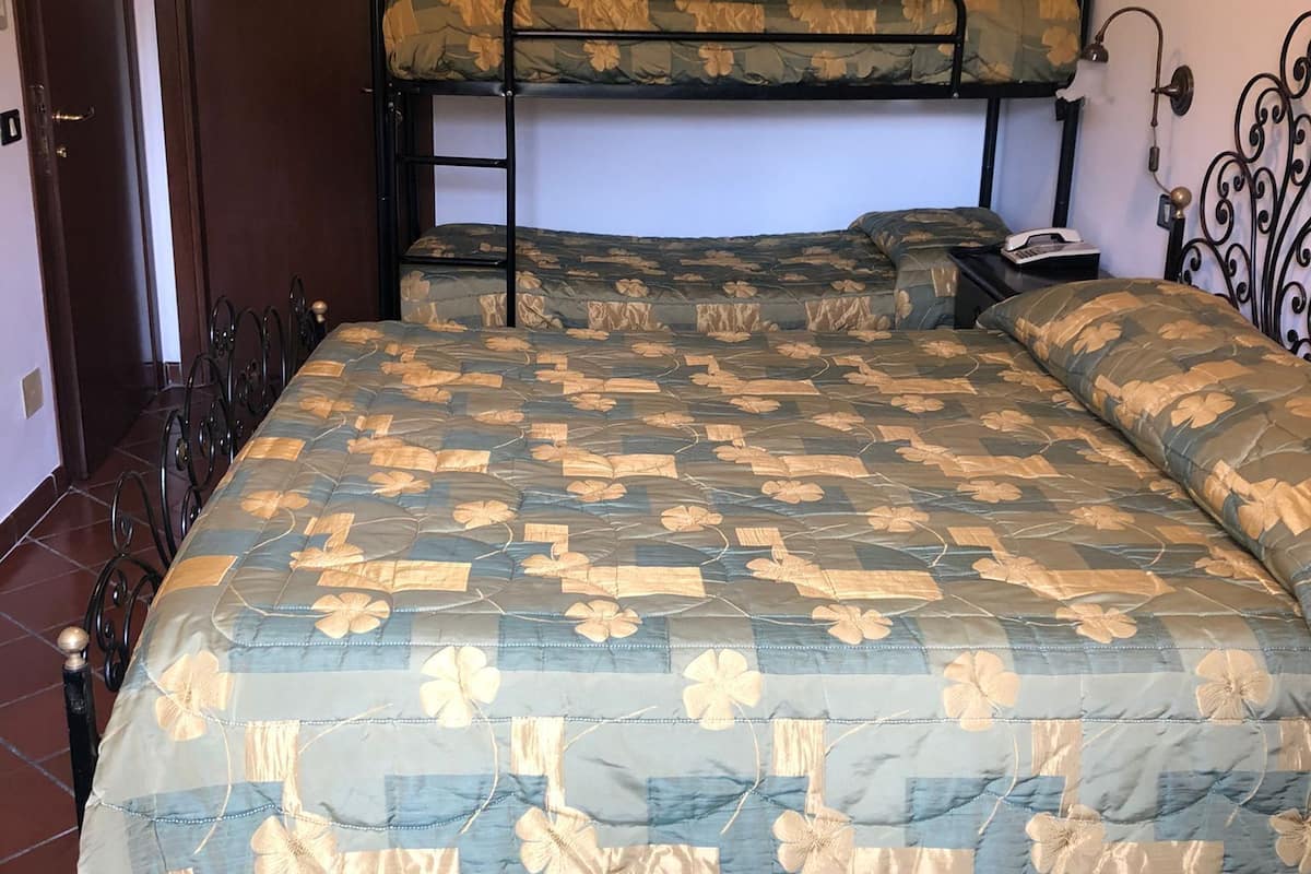 Una habitación con una cama individual, una litera y una mesita de noche con una lámpara.