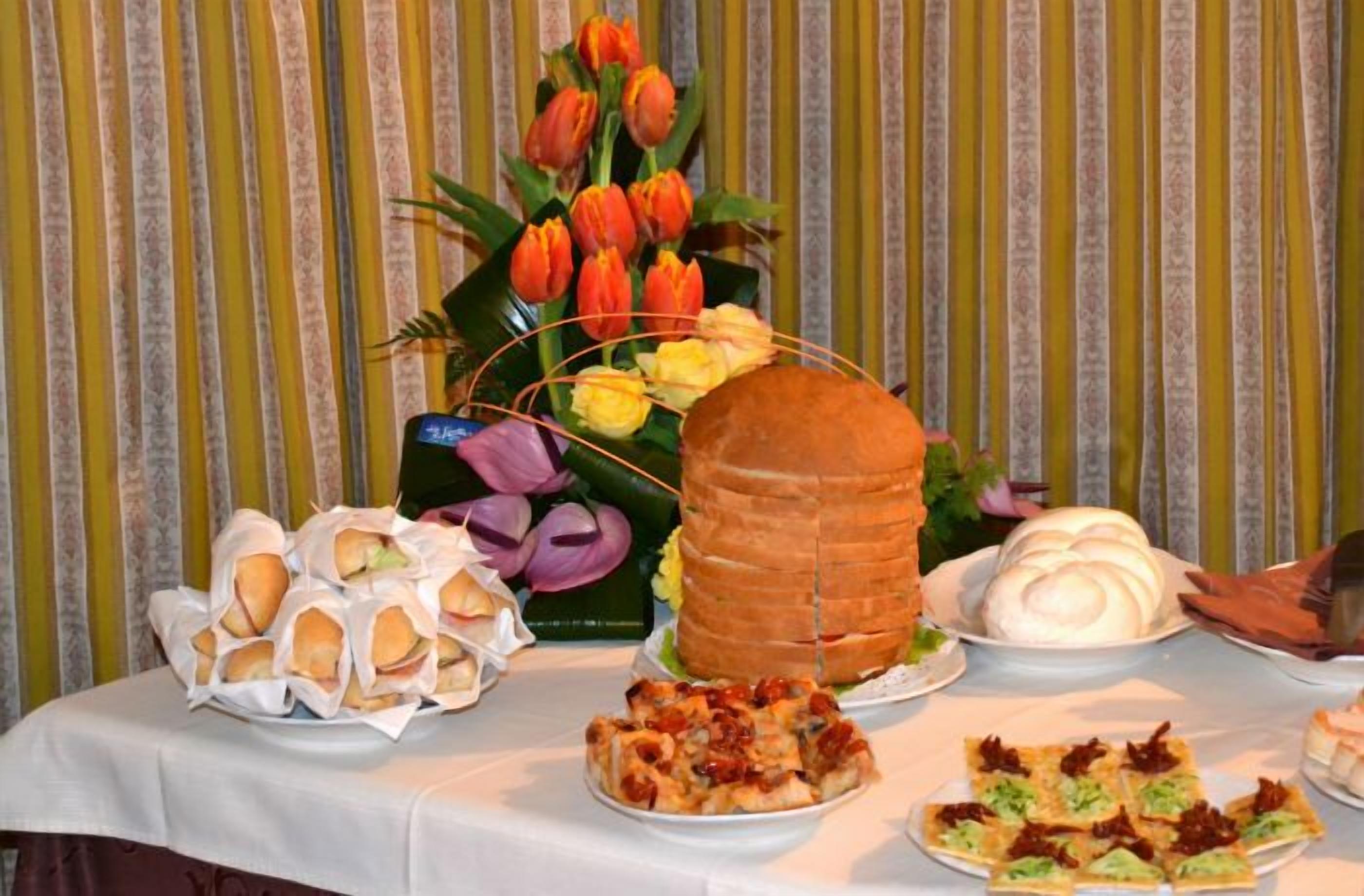 Ein Buffet mit verschiedenen Speisen, darunter Sandwiches, ein großes Brötchen und dekorierte Gebäckstücke.