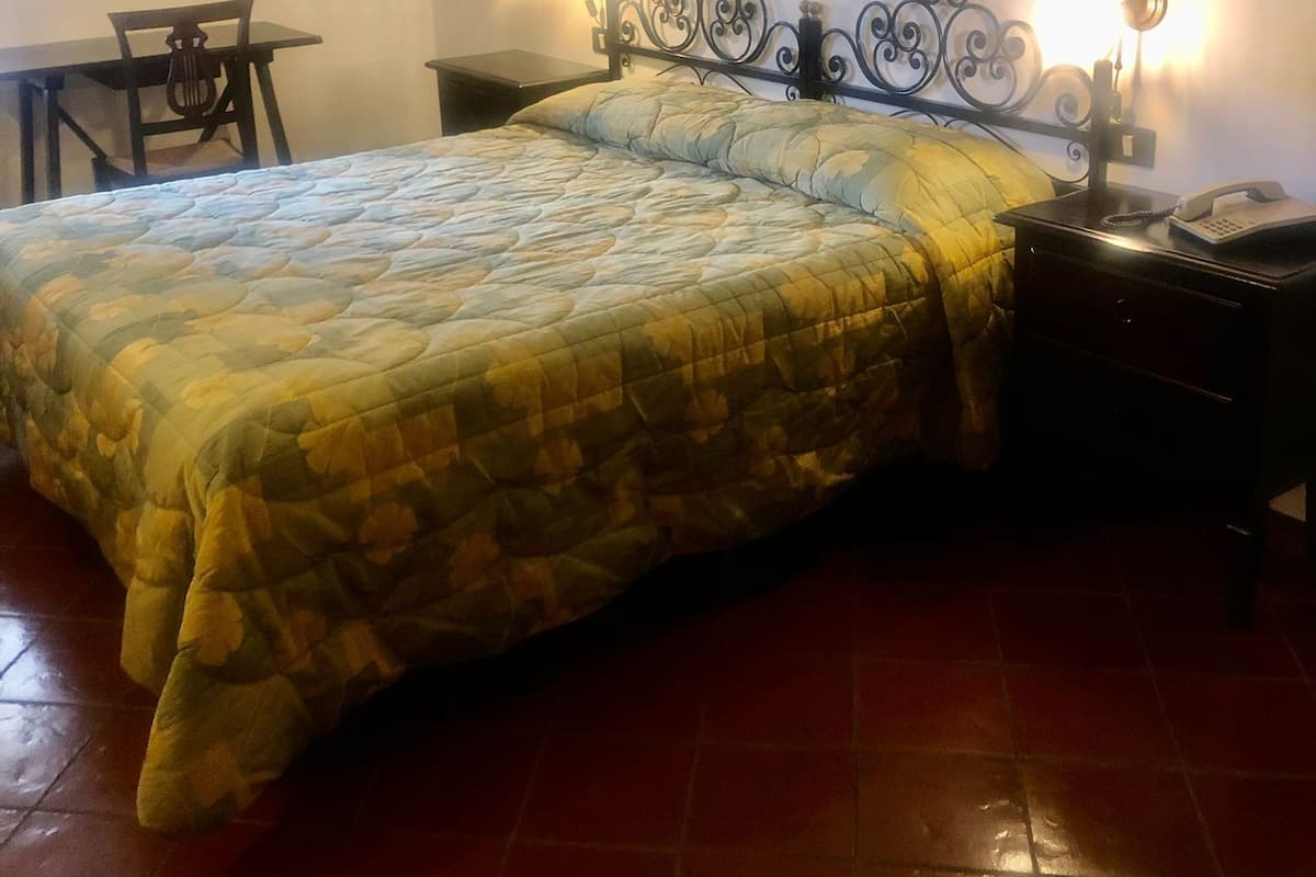 Un dormitorio con una cama, dos mesitas de noche, una silla y un escritorio.