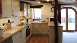 A kitchen with wooden cabinets, a sink, and a window. - Garth Cottage (Brampton)