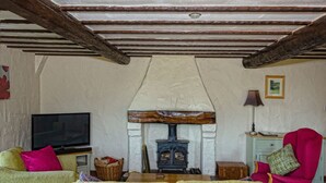 A cozy living room with a fireplace, a television, and comfortable seating. - Garth Cottage (Brampton)
