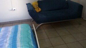 A room with a bed, a blue sofa, a teddy bear, a flat-screen TV, and a wall-mounted picture. - Bed and Breakfast Priscilla (Regalbuto)