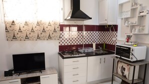 A compact kitchen with a TV, stove, microwave, and white cabinets. - Charmin & Trendy Apartment Marsa Beach (La Marsa)