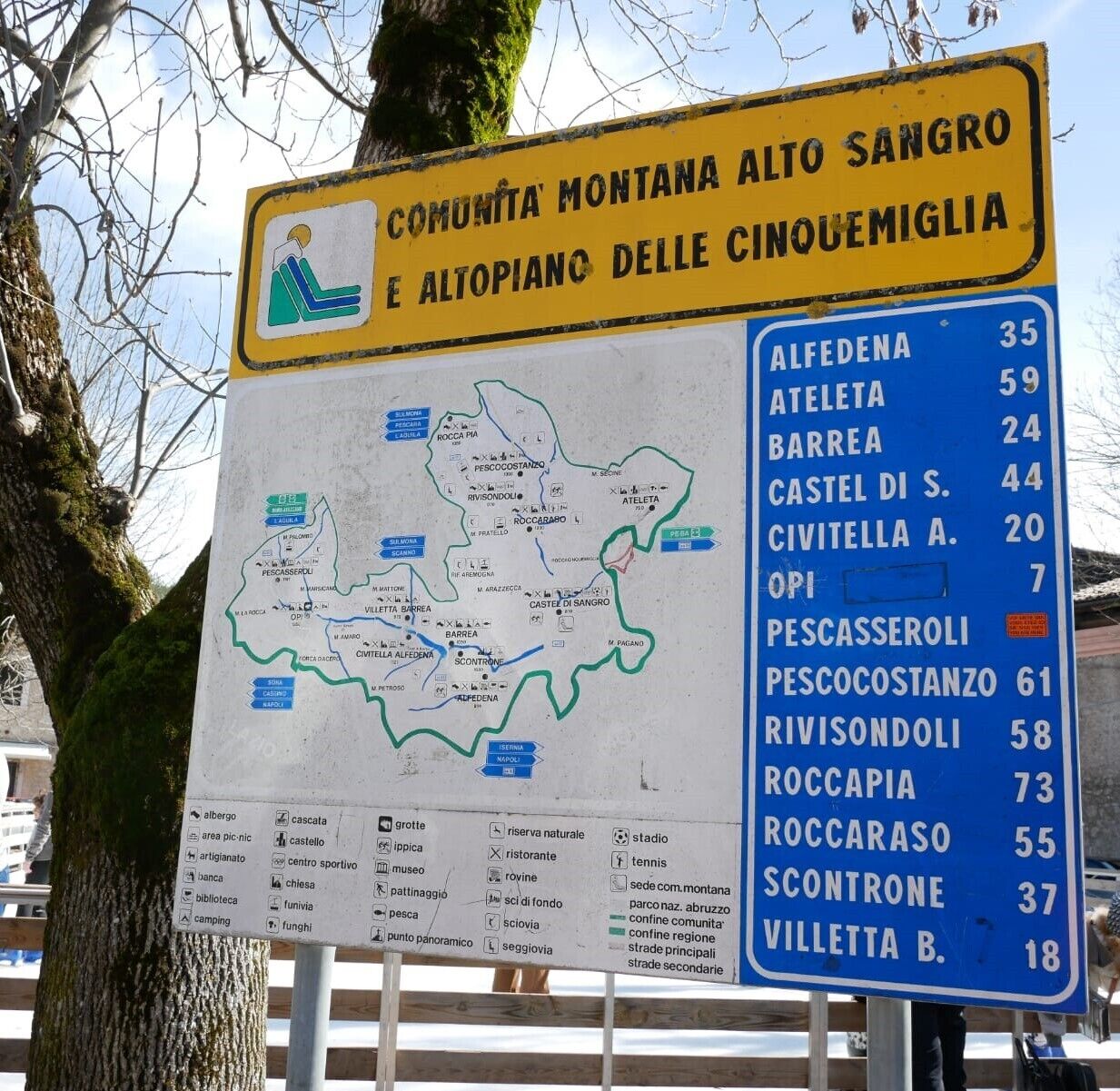A sign with a map and distance markers for various locations.