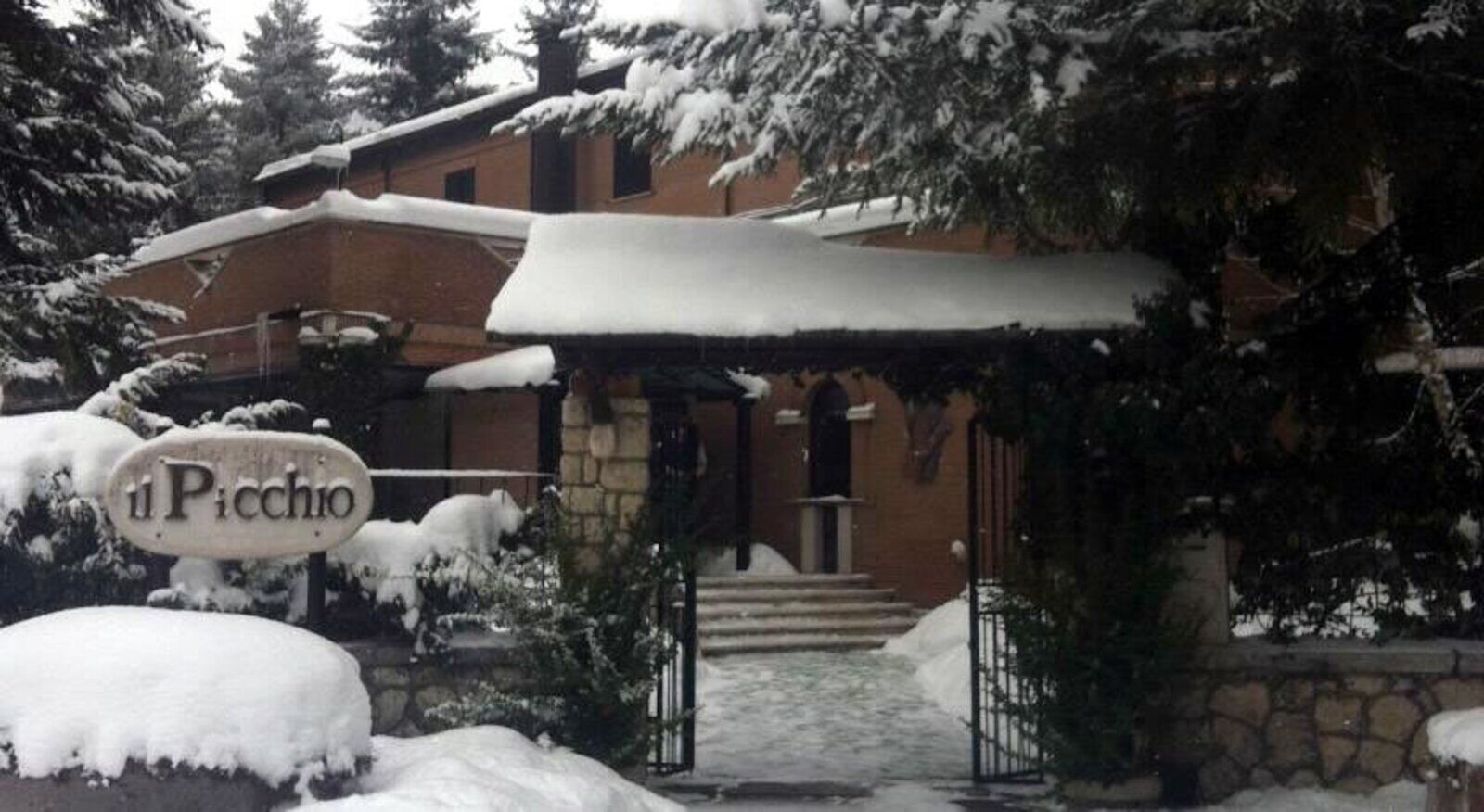 Un edificio con una entrada cubierta de nieve y un letrero que dice "Il Picchio".