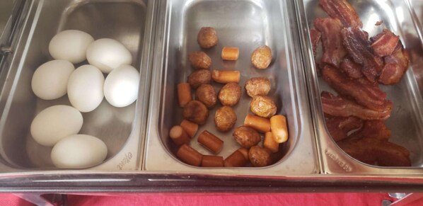 A buffet with three sections: eggs, sausages, and bacon.