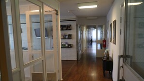 A hallway with wooden flooring, glass doors, and framed pictures on the walls. - Vingåkers Hotell (Vingåker)