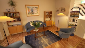 Una sala de estar con un sofá, sillones, una mesa de centro y una estantería.