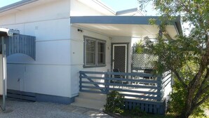 A two-story building with a covered porch and a gated entrance. - Blue Haven - Pet friendly Cottage  (Iluka)