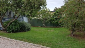 A grassy yard with trees and a fence. - Blue Haven - Pet friendly Cottage  (Iluka)