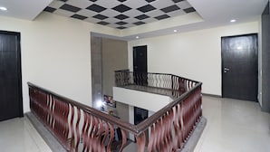 A modern interior with a checkered ceiling, a wooden railing, and a tiled floor. - OYO 24624 Kaycee Residency (Gurugram)