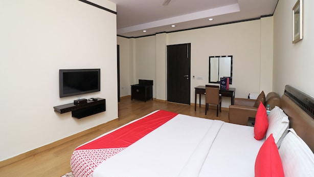 A modern hotel room with a bed, a TV, a desk, and a chair. - OYO 24624 Kaycee Residency (Gurugram)