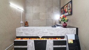 A reception desk with a marble top, a framed artwork on the wall, and a vase with flowers. - OYO 24624 Kaycee Residency (Gurugram)
