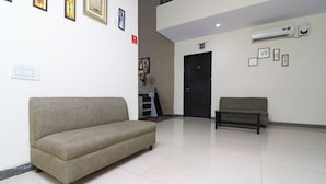 A modern hotel lobby with a beige sofa, a bench, and a door. - OYO 24624 Kaycee Residency (Gurugram)