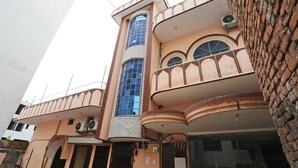 Un immeuble à plusieurs étages doté d’un balcon incurvé, d’une tour centrale avec une façade en verre et de plusieurs unités de climatisation.