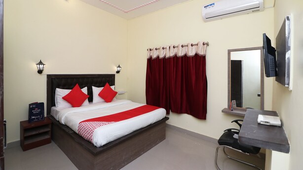 Une chambre d’hôtel bien rangée, avec un lit, une table de chevet, une télévision et un appareil de climatisation.