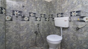 Une salle de bain comprenant des toilettes, une douche et un mur orné de carreaux à motifs floraux.