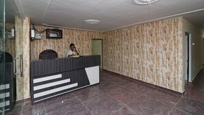Un espace d’accueil avec un mur décoré d’un motif en bois, un comptoir d’accueil et une personne derrière ce comptoir.