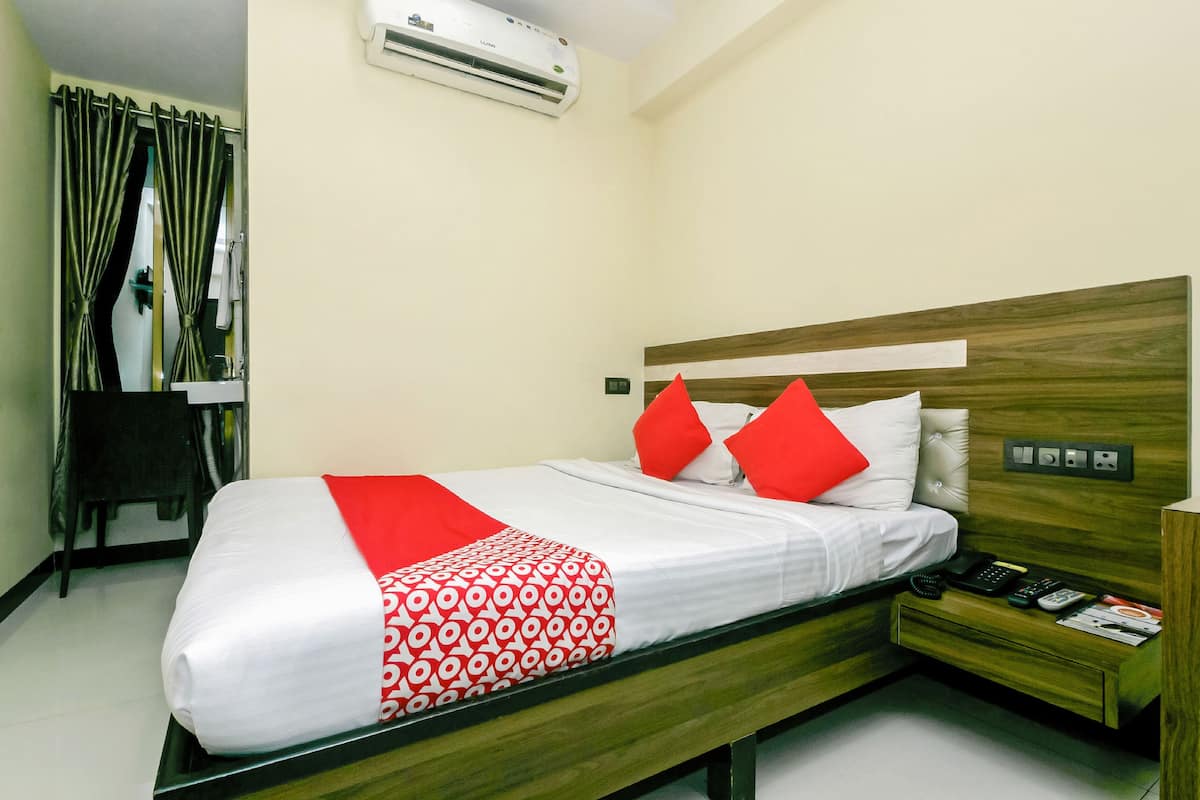 Una habitación de hotel con cama, mesita de noche y equipo de aire acondicionado.