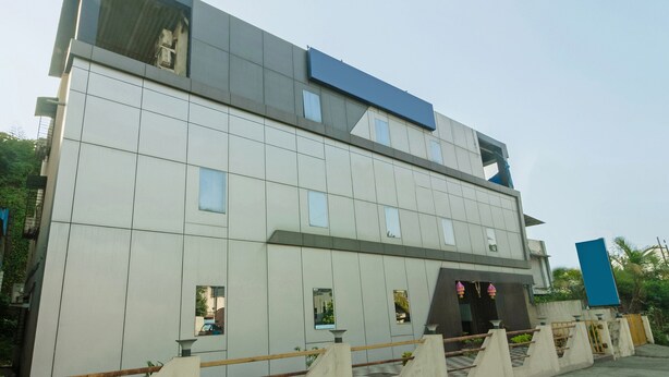 A modern building with a flat roof, large windows, and a prominent blue sign. - OYO 23656 Parimeet Hotel (Navi Mumbai)