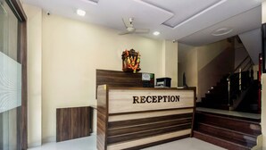 A reception desk with a sign that reads "RECEPTION" and a garland above it. - OYO 23656 Parimeet Hotel (Navi Mumbai)
