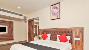 Une chambre d’hôtel moderne avec un grand lit, une tête de lit en bois et un téléviseur à écran plat fixé au mur.