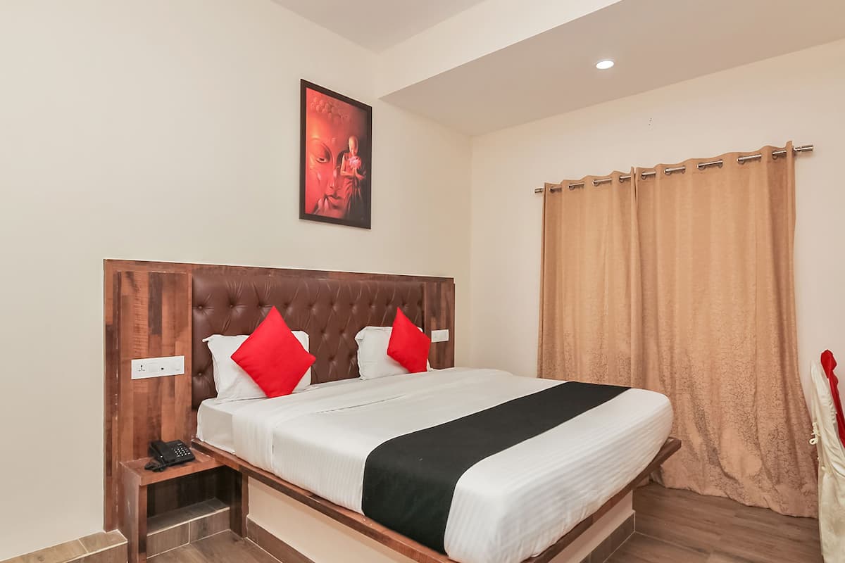 A neatly made bed with a wooden headboard, two red pillows, and a black accent pillow.