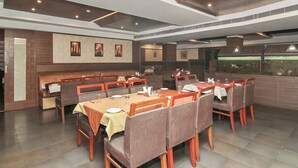 Un restaurant avec de nombreuses tables et des banquettes, un sol carrelé et un aquarium en arrière-plan.